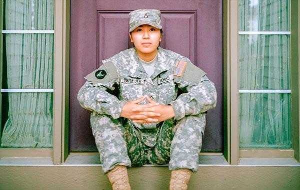 woman in us army uniform sitting in front of a door